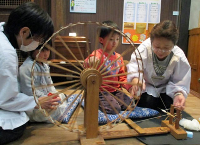 体験講座（糸車）の補助をするボランティアさん